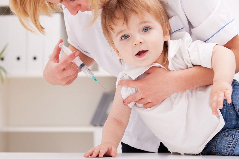 Doctor giving a child injection in arm