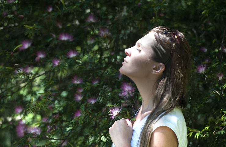 Donna in mezzo alla natura che respira profondamente