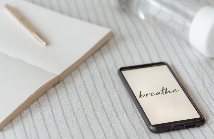 Smartphone con scritto breathe e quaderno con penna