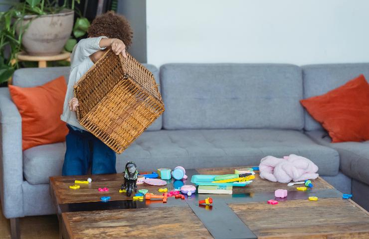 Bambino ribalta una cesta di giochi sul tavolo