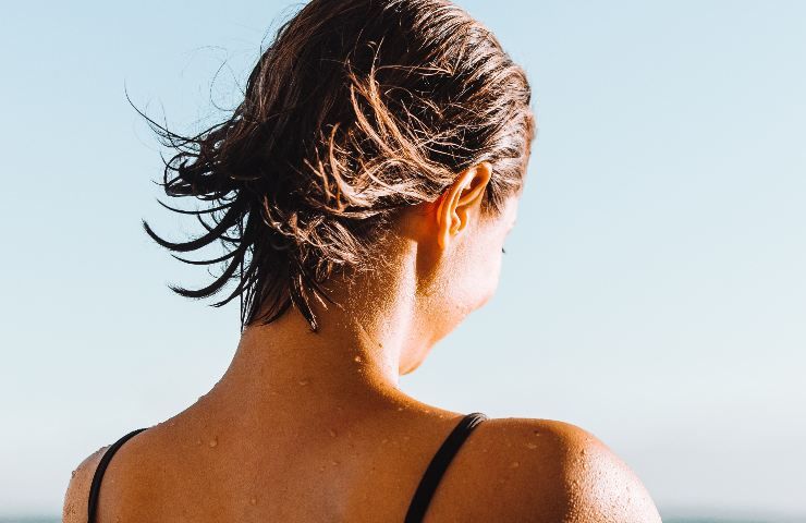 Donna girata di schiena prende il sole in costume da bagno