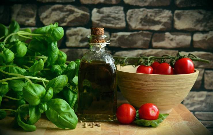 Tavola con olio d'oliva, pomodori e basilico