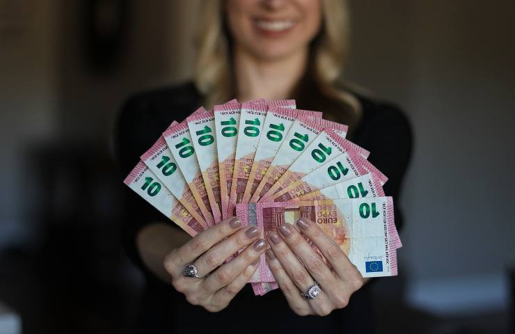 Donna regge tra le mani varie banconote da dieci euro