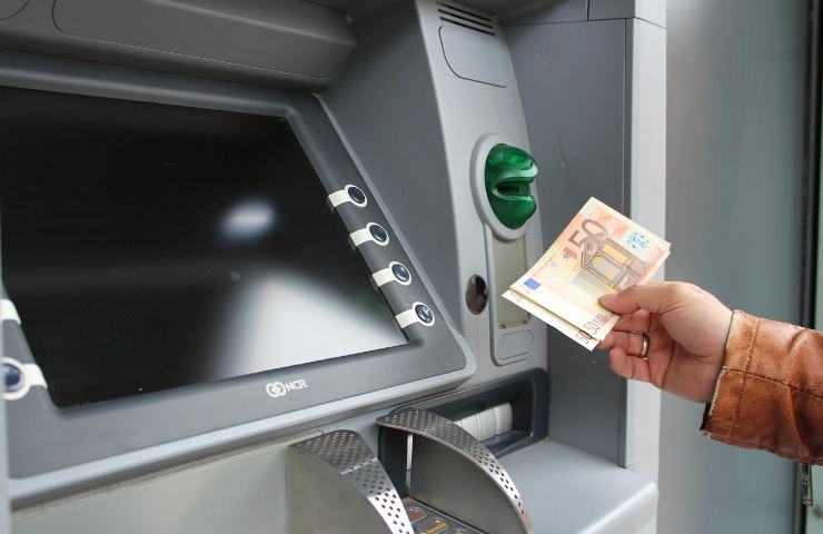 Persona preleva denaro allo sportello ATM