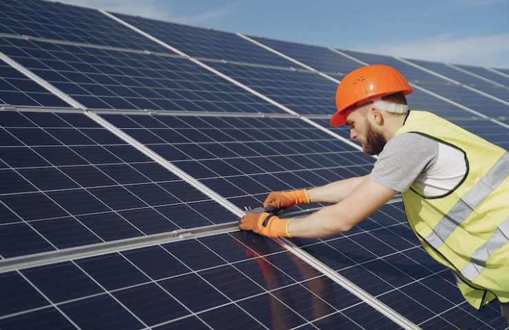 Un operaio al lavoro su dei pannelli fotovoltaici