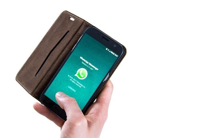 Una persona regge in mano un telefonino con Whatsapp avviato