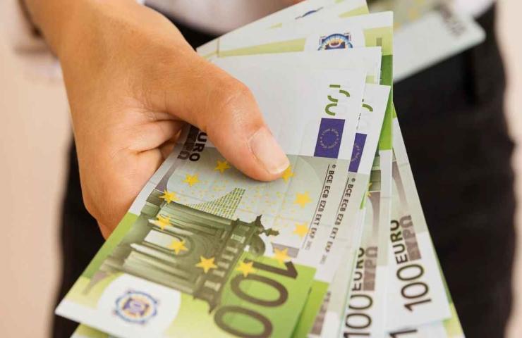 Uomo porge varie banconote da cento euro