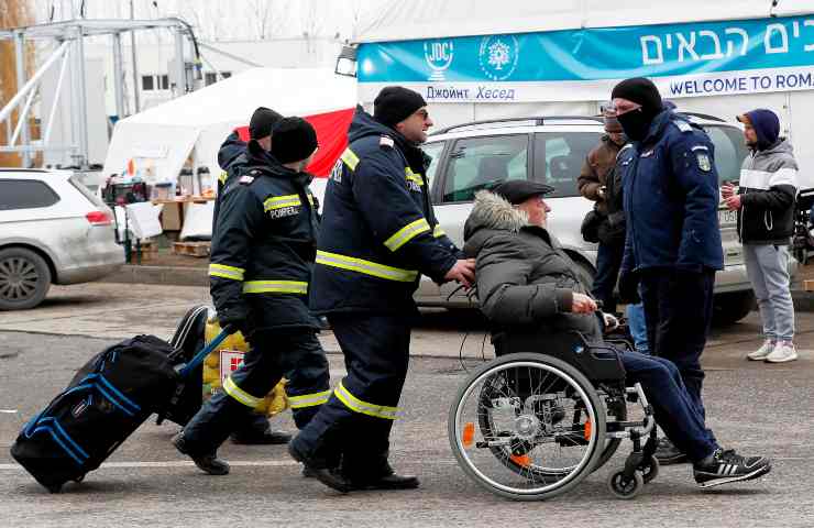 Dei volontari badano ad un uomo disabile