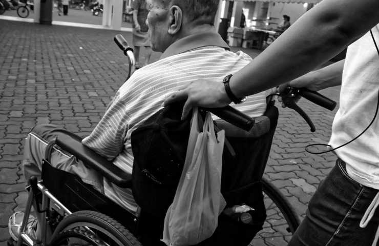 Un individuo spinge una persona su una sedia a rotelle