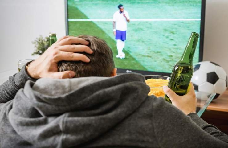 Un uomo guarda una partita di calcio in tv