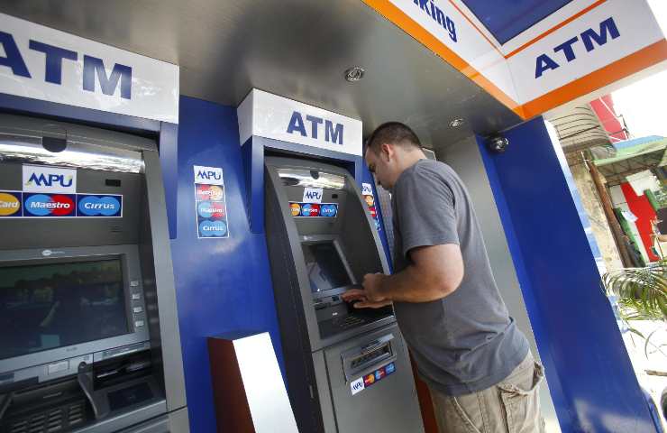 Un uomo mentre preleva dei soldi allo sportello ATM
