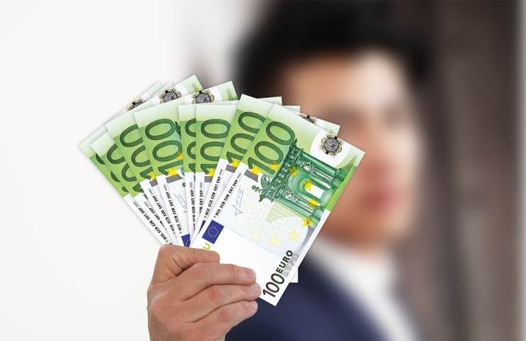 Un uomo regge in mano svariate banconote da cento euro