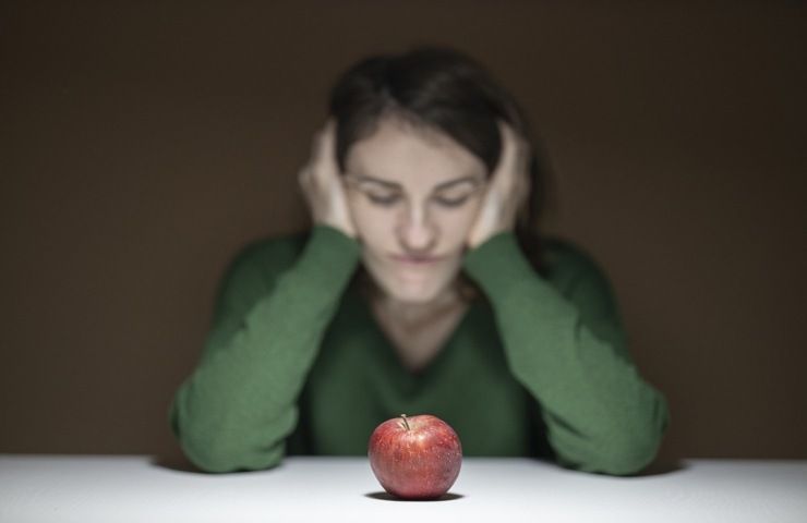 Una donna affaticata con una mela davanti