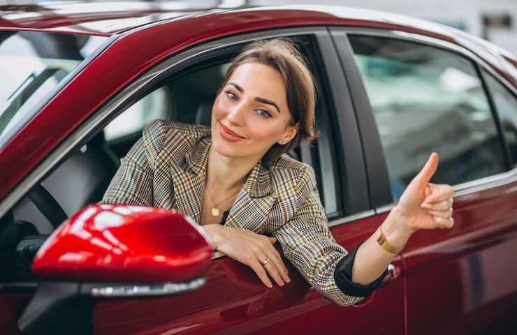 Una donna contenta alla guida della propria auto