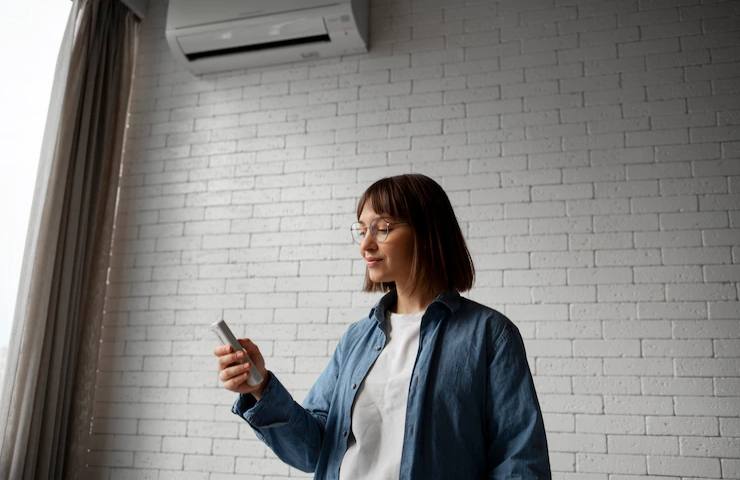 Una donna tiene in mano il telecomando del condizionatore