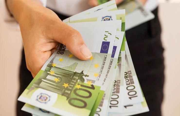 Una persona porge delle banconote da cento euro