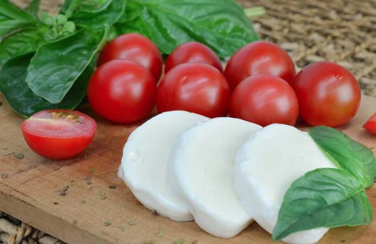 Della mozzarella affettata con pomodori e basilico