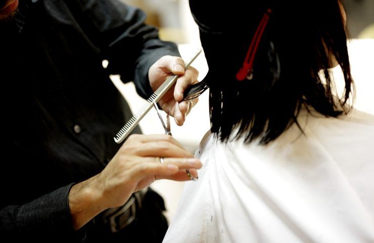 Un parrucchiere mentre taglia i capelli ad una ragazza