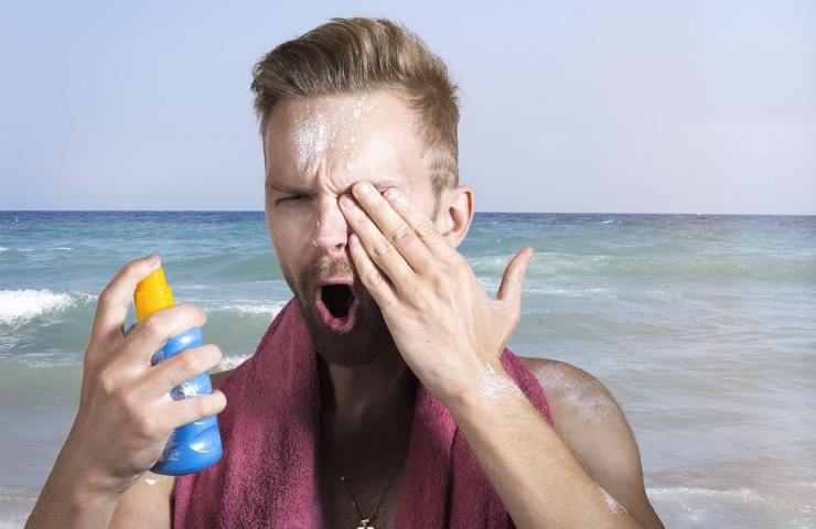Un uomo si spruzza negli occhi lo spray solare