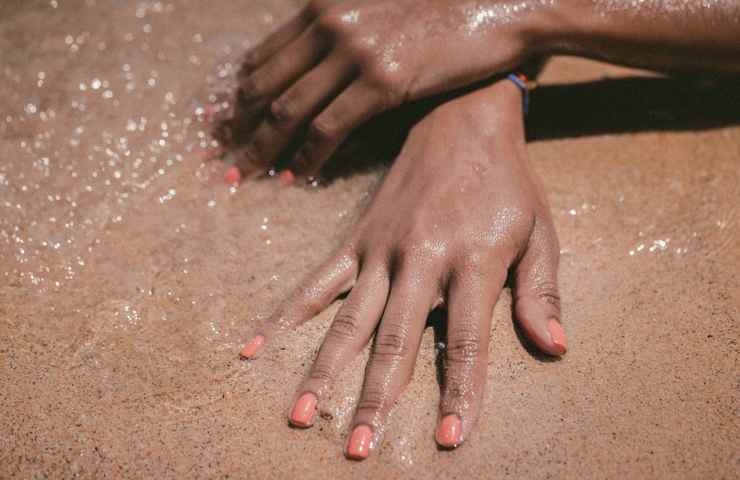 Le mani di una donna stesa sulla riva