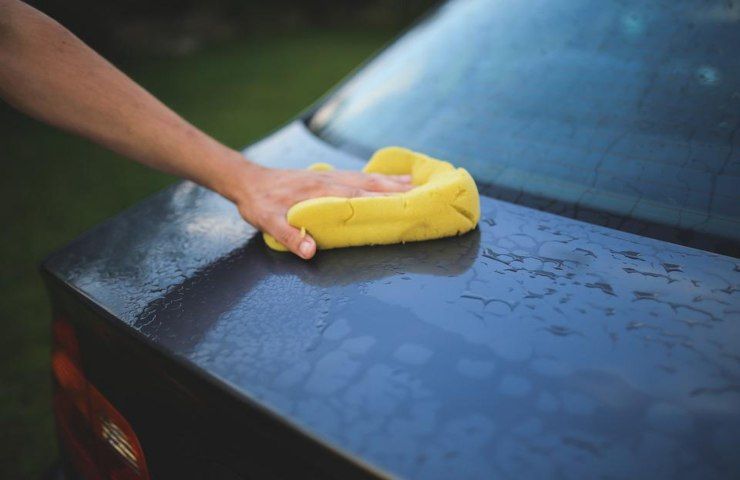 Un uomo mentre lava l'auto