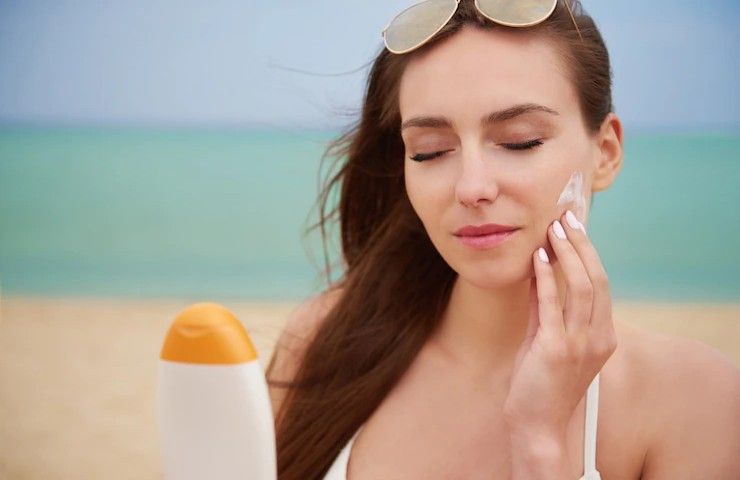 Una donna applica della crema solare sul proprio viso