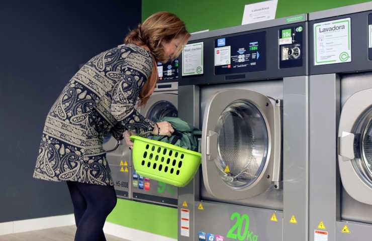 Una donna mentre carica una lavatrice