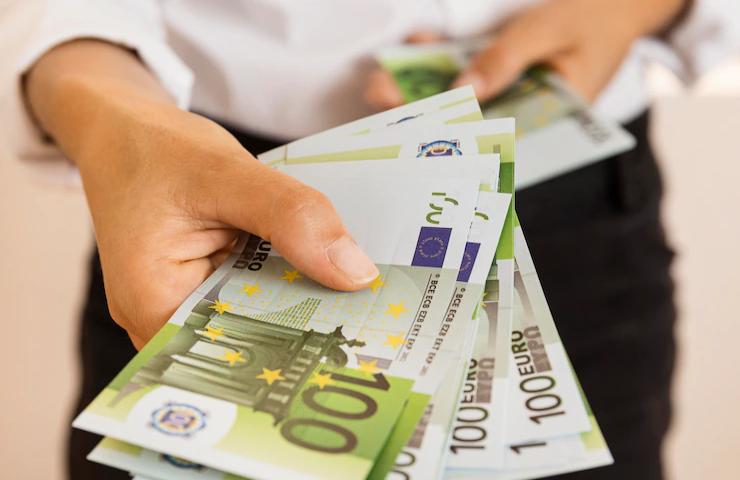 Una persona porge delle banconote da cento euro