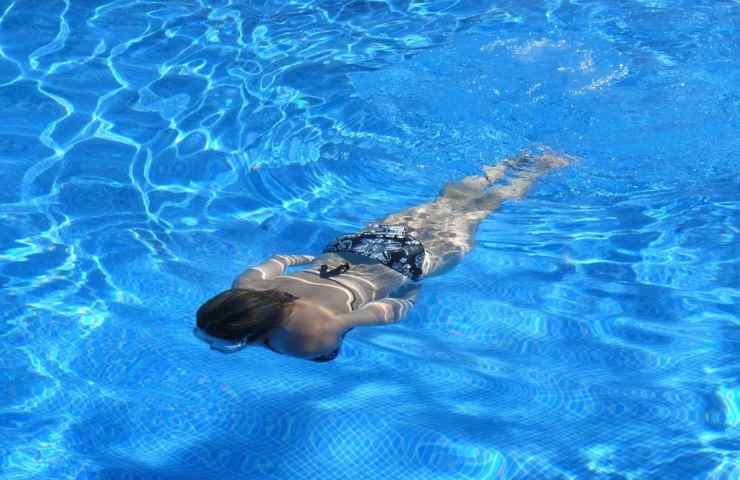 Una ragazza nuota sott'acqua in piscina