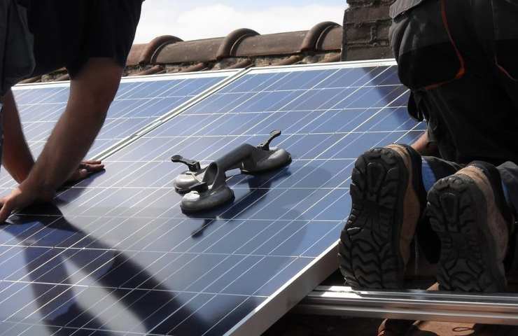 Due operai installano dei pannelli solari su di un tetto