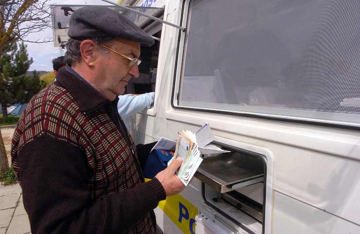 Un uomo preleva la propria pensione da uno sportello di Poste Italiane
