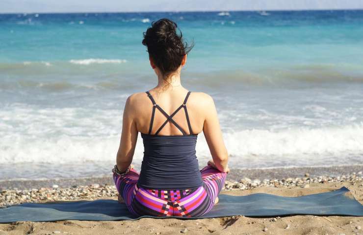 Una donna fa yoga su una spiaggia incontaminata