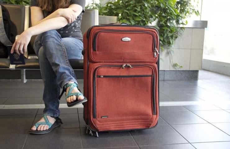 Una donna con una valigia accanto a sé