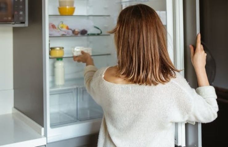 Una donna davanti ad un frigorifero aperto