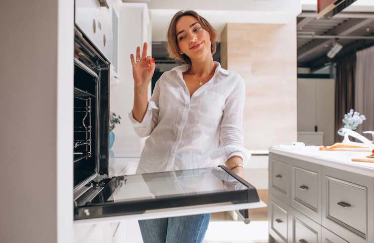 Una donna soddisfatta dopo avere pulito il forno