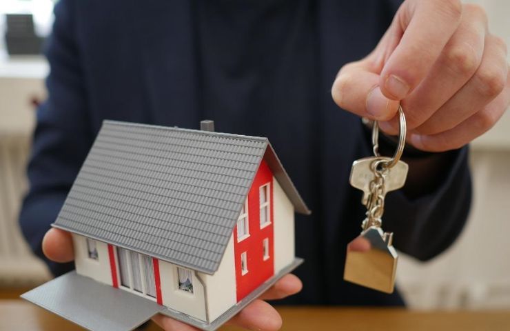 Una persona regge il modellino di una casa e delle chiavi