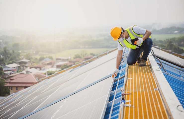 Un operaio controlla dei pannelli solari su un tetto