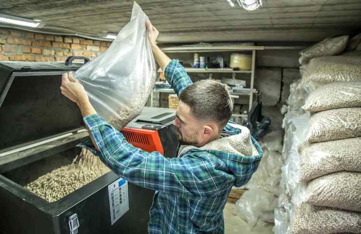 Un uomo svuota un sacco di pellet