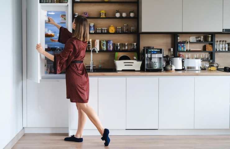 Una donna apre il frigorifero in casa