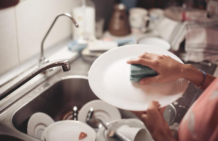Una donna mentre lava le stoviglie a mano