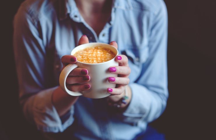 Una donna regge una tazza di caffè macchiato