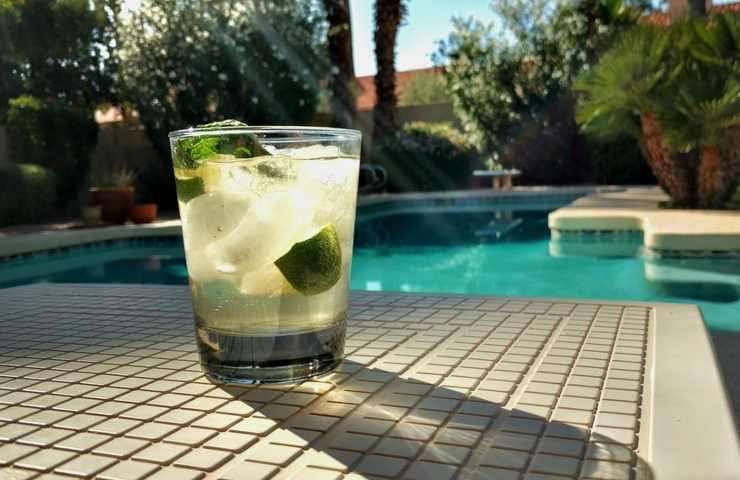 Un bicchiere riempito con dell'acqua di cocco ai bordi di una piscina
