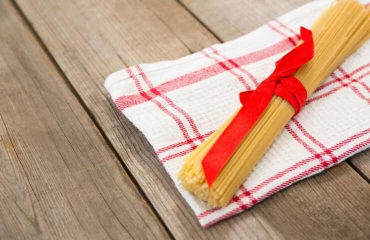 Un panno della cucina sotto a degli spaghetti crudi