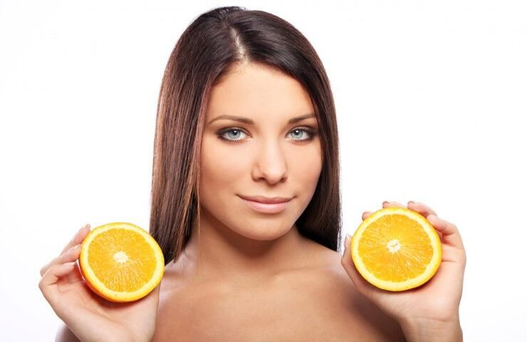 Una donna bellissima regge una arancia affettata a metà