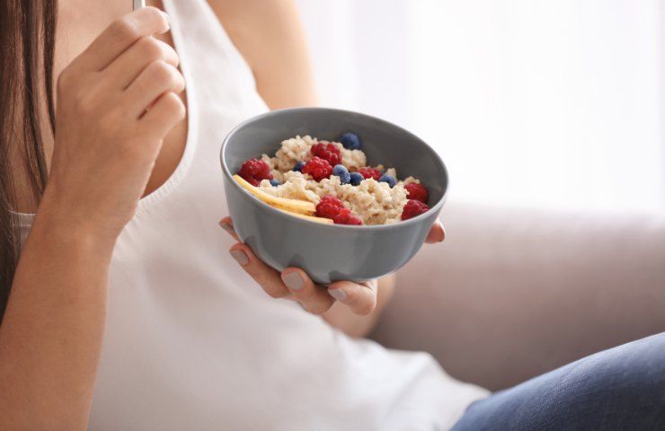 Una donna mangia fiocchi d'avena con frutti di bosco