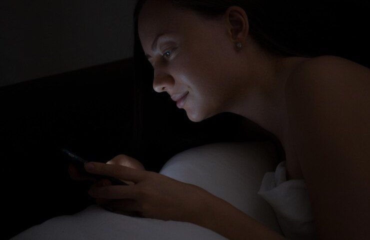 Una donna mentre utilizza il telefonino a letto