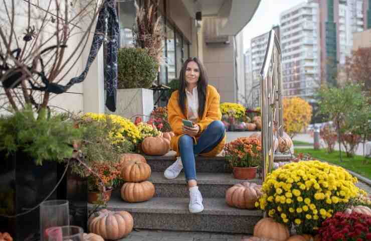 Una donna su di una balconata agghindata a tema autunnale