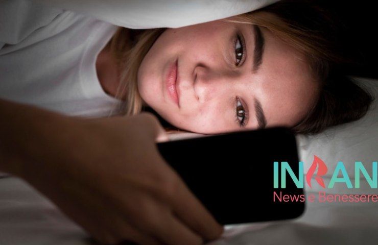 Una ragazza a letto con lo smartphone