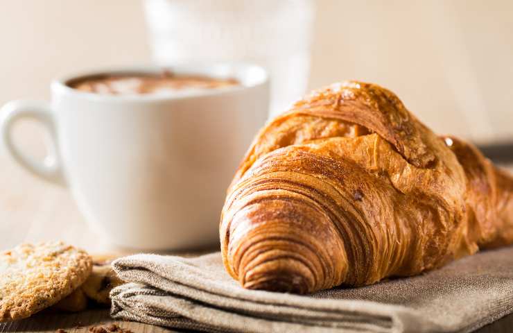 Un cornetto ed un cappuccino con dei biscotti