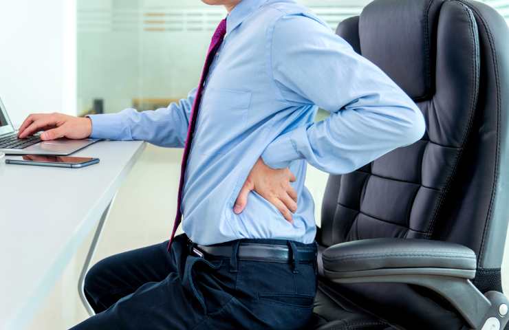 Un uomo seduto in ufficio con il mal di schiena